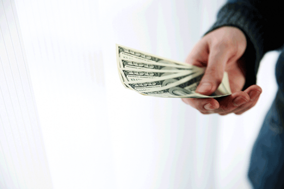 a man's hand holding several $100 dollar bills