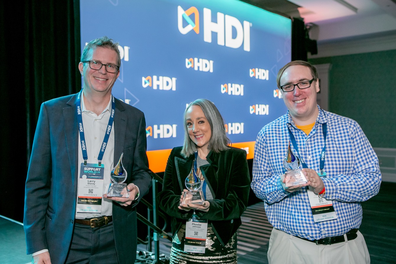 Larry Storey, Phoebe Johnson, and Steve Aker smile brightly and hold HDI award trophies