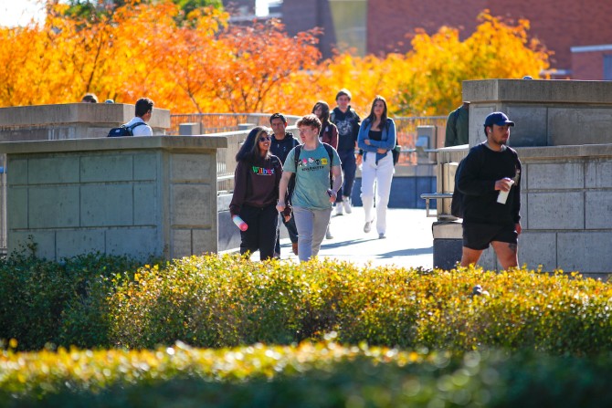 Students walking with a background of fall trees 